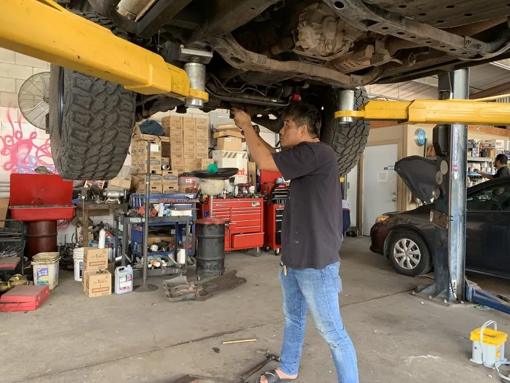 A mechanic working under a car on the lift at Lim's Auto Service